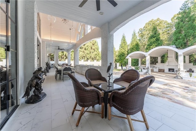 view of patio / terrace featuring an outdoor living space with a fireplace, outdoor dining area, and a ceiling fan