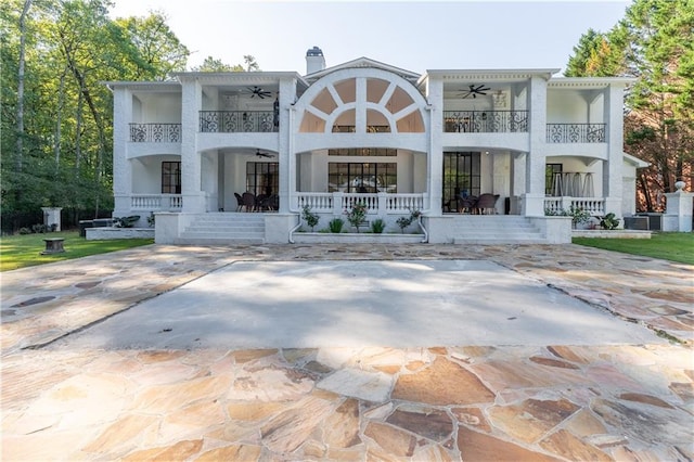 rear view of property featuring stucco siding, a balcony, a porch, and a ceiling fan