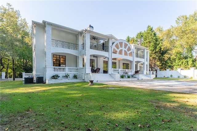 rear view of house featuring covered porch, a balcony, a lawn, and a ceiling fan