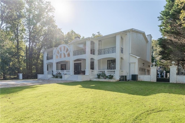 back of property with a balcony, central air condition unit, a yard, and covered porch