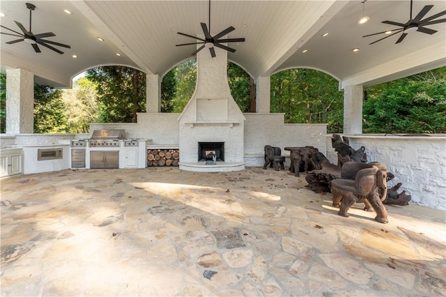 view of patio with grilling area, a ceiling fan, area for grilling, and a fireplace