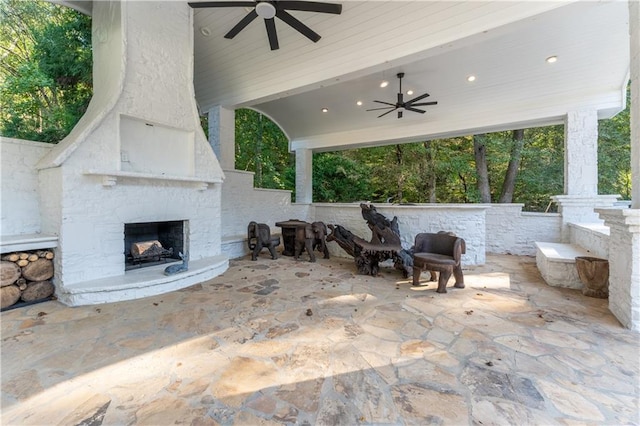 view of patio featuring an outdoor stone fireplace and a ceiling fan