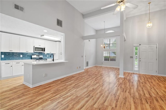 3549 Daventry Ln NW, Kennesaw, GA 30144 - kitchen with a towering ceiling, stainless steel appliances, light wood finished floors, white cabinets, and light countertops