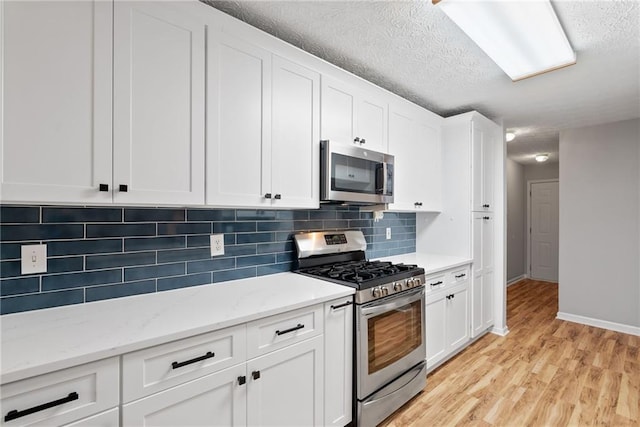 3549 Daventry Ln NW, Kennesaw, GA 30144 - kitchen with appliances with stainless steel finishes, light wood-style flooring, tasteful backsplash, white cabinets, and a textured ceiling
