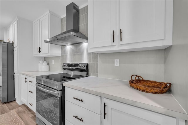 551 Fern Valley Trl NE, Clarkesville, GA 30523 - kitchen featuring wall chimney range hood, stainless steel electric range oven, freestanding refrigerator, white cabinetry, and light wood-type flooring