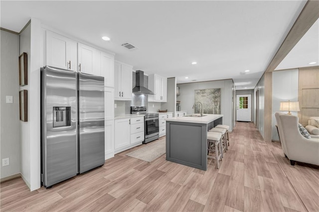 551 Fern Valley Trl NE, Clarkesville, GA 30523 - kitchen with stainless steel appliances, wall chimney range hood, white cabinetry, light wood-type flooring, and light countertops