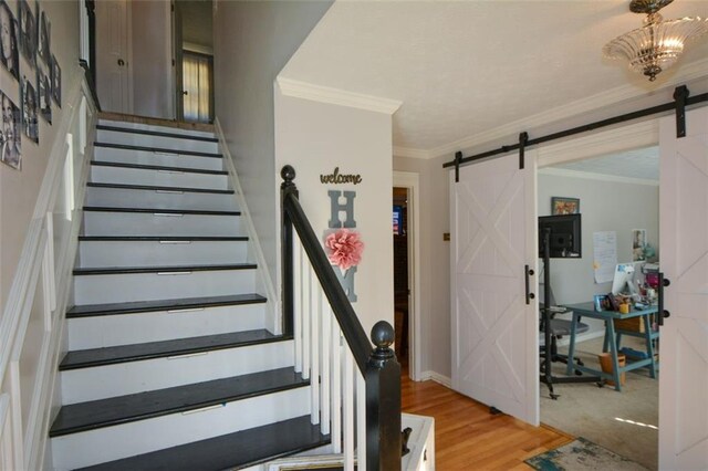 stairway with hardwood / wood-style flooring, crown molding, and a barn door