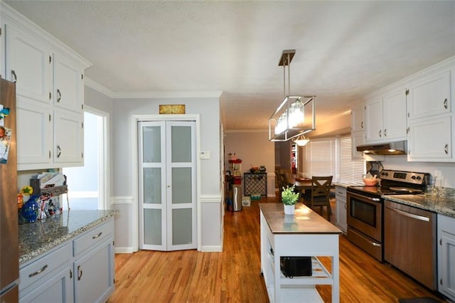 kitchen with white cabinetry, wood counters, appliances with stainless steel finishes, and hanging light fixtures