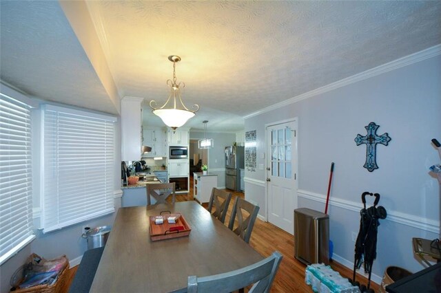 dining space featuring crown molding, a textured ceiling, and light hardwood / wood-style flooring