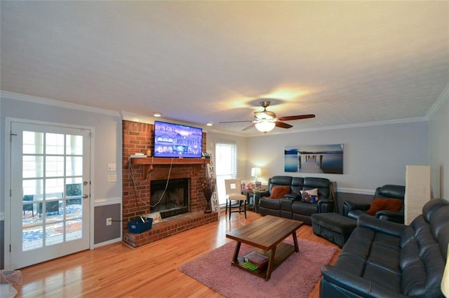 living room featuring hardwood / wood-style floors, crown molding, a fireplace, and ceiling fan