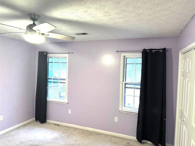 spare room featuring ceiling fan, light colored carpet, and a textured ceiling