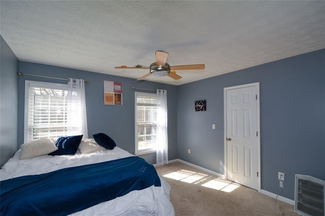 bedroom featuring light carpet, a textured ceiling, and ceiling fan