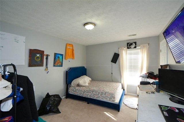 bedroom with light colored carpet and a textured ceiling