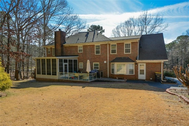 rear view of house featuring a sunroom and a lawn