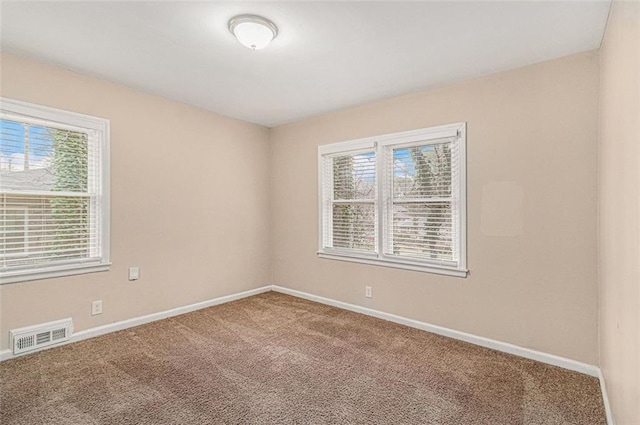 empty room with a healthy amount of sunlight, visible vents, carpet floors, and baseboards