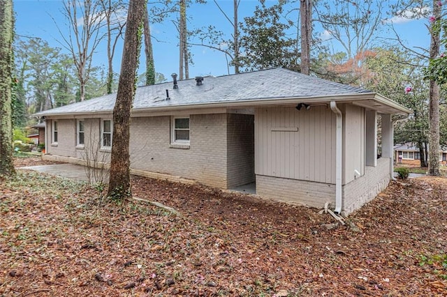 back of property with a patio area, brick siding, and a shingled roof