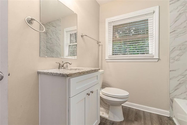 full bath with a wealth of natural light, toilet, vanity, and wood finished floors