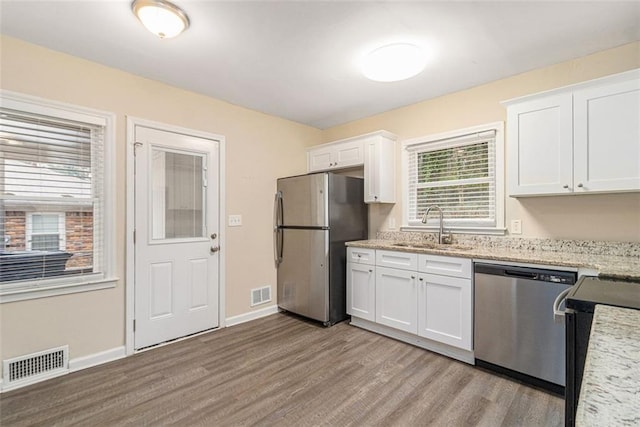 kitchen with visible vents, white cabinets, stainless steel appliances, and a sink