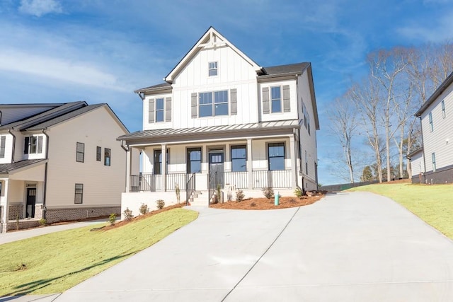 modern inspired farmhouse with a standing seam roof, covered porch, a front lawn, board and batten siding, and metal roof