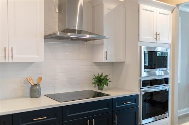 kitchen with decorative backsplash, white cabinets, wall chimney exhaust hood, and stainless steel appliances