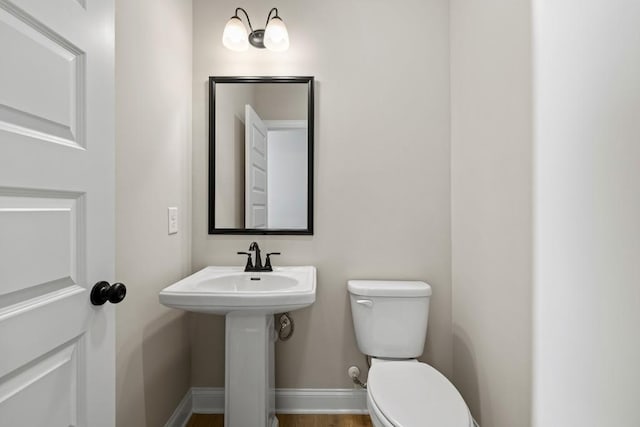 bathroom with toilet, baseboards, and a sink