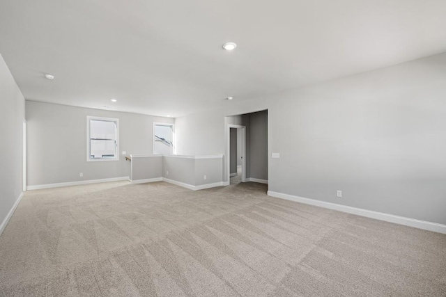 empty room featuring recessed lighting, baseboards, and light carpet