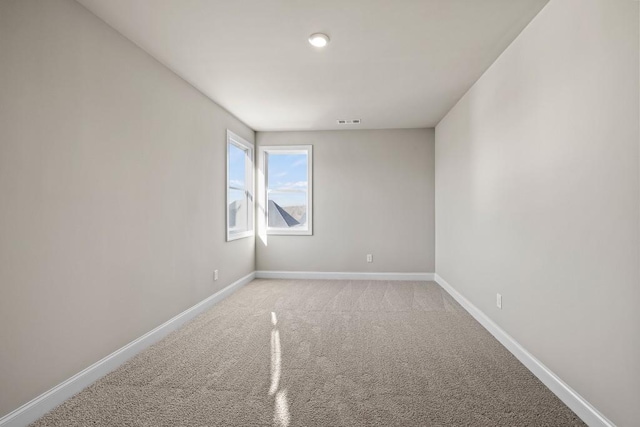 carpeted empty room featuring baseboards and visible vents