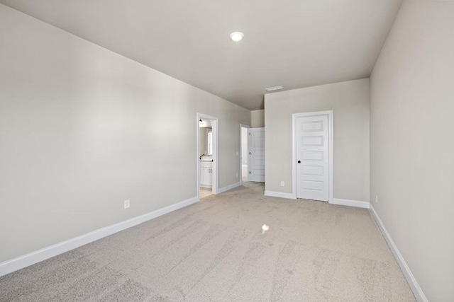 unfurnished bedroom featuring light colored carpet, connected bathroom, and baseboards