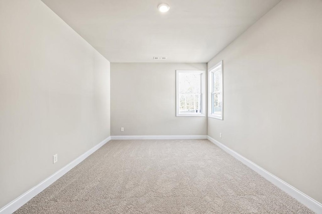 unfurnished room featuring visible vents, light colored carpet, and baseboards