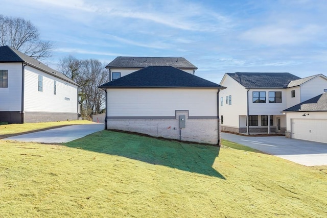 back of house with a garage, a lawn, roof with shingles, and brick siding