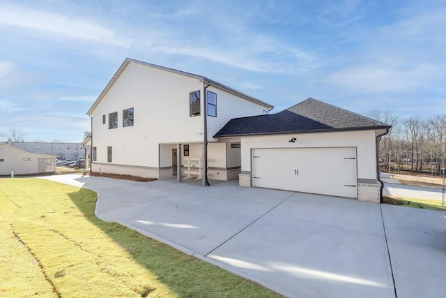 view of side of home with concrete driveway, an attached garage, and roof with shingles