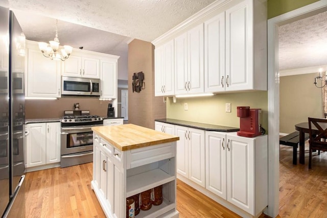 1134 Roscoe Rd, Newnan, GA 30263 - kitchen featuring appliances with stainless steel finishes, a chandelier, a textured ceiling, butcher block counters, and white cabinets