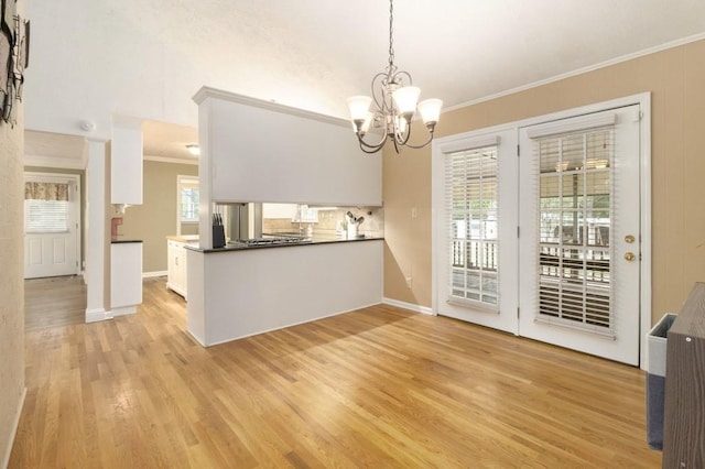 1134 Roscoe Rd, Newnan, GA 30263 - kitchen with crown molding, light wood-style floors, a chandelier, white cabinets, and dark countertops
