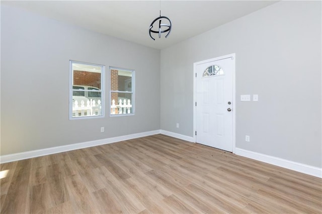 empty room featuring a chandelier, a healthy amount of sunlight, and light hardwood / wood-style floors