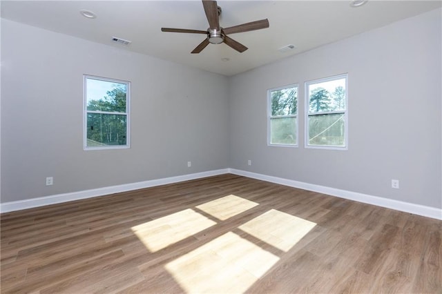 unfurnished room with a wealth of natural light, ceiling fan, and hardwood / wood-style flooring