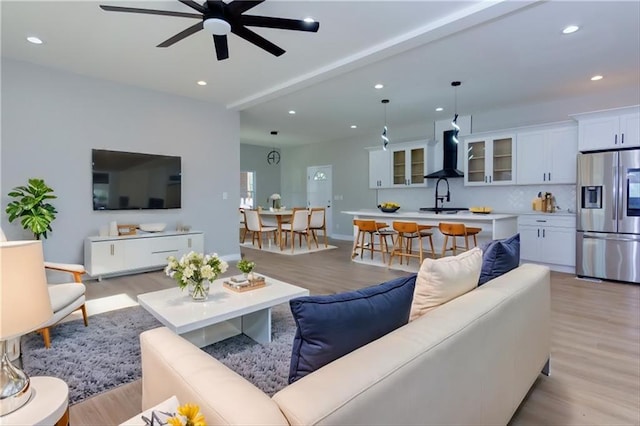 living room with beam ceiling, ceiling fan, and light hardwood / wood-style floors