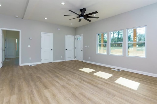 unfurnished bedroom featuring beamed ceiling, light hardwood / wood-style floors, ceiling fan, and multiple closets