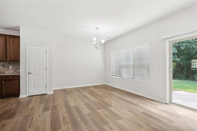 unfurnished dining area with an inviting chandelier and light hardwood / wood-style floors