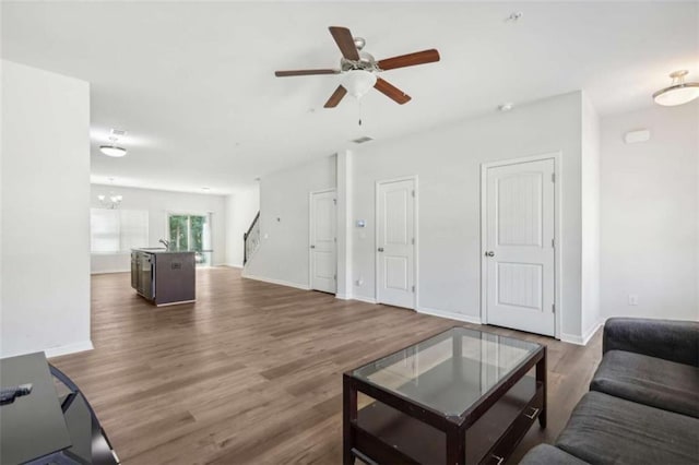 living room featuring ceiling fan with notable chandelier and dark hardwood / wood-style floors