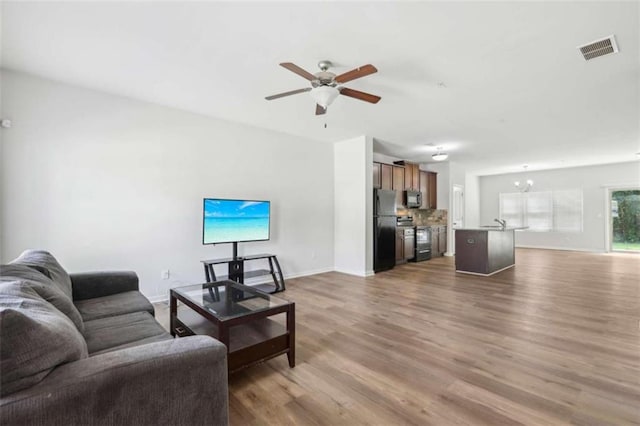 living room with dark hardwood / wood-style flooring, sink, and ceiling fan with notable chandelier