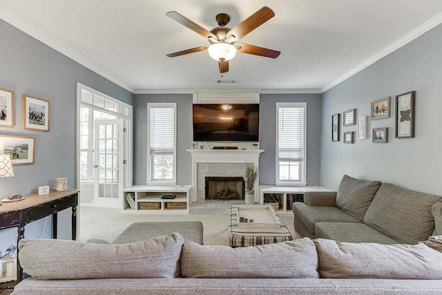 carpeted living room with visible vents, a ceiling fan, a large fireplace, and ornamental molding