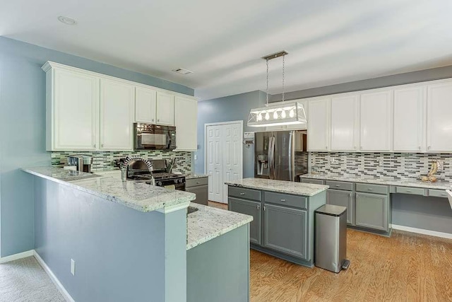 kitchen with range with gas cooktop, decorative backsplash, gray cabinetry, black microwave, and stainless steel refrigerator with ice dispenser