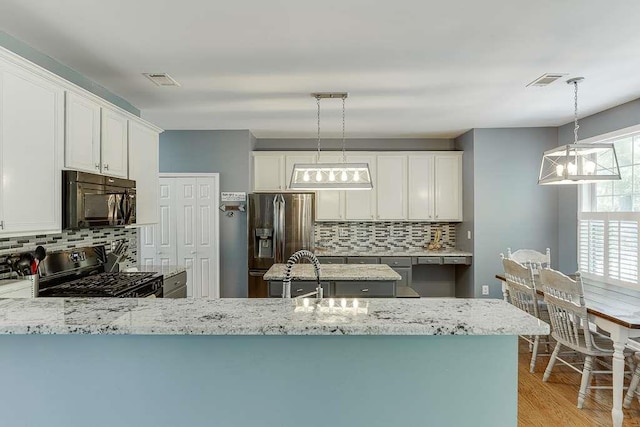 kitchen featuring backsplash, light stone countertops, stainless steel appliances, and visible vents