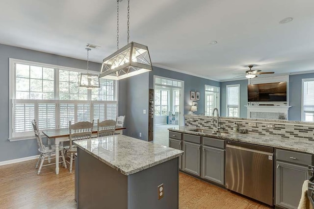 kitchen featuring dishwasher, a sink, a kitchen island, and gray cabinets