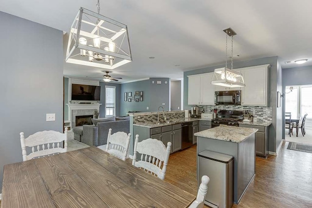 dining area featuring wood finished floors, a fireplace, and ceiling fan