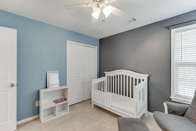 carpeted bedroom with a nursery area, multiple windows, visible vents, and a closet
