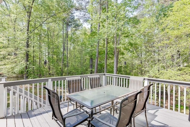 deck with outdoor dining area and a view of trees