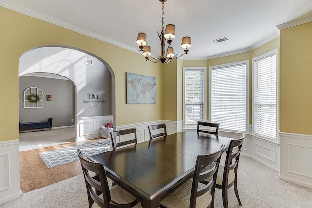 dining area with a wealth of natural light, arched walkways, visible vents, and an inviting chandelier