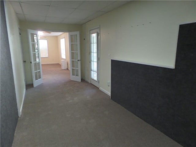 hallway featuring french doors, carpet floors, and a drop ceiling