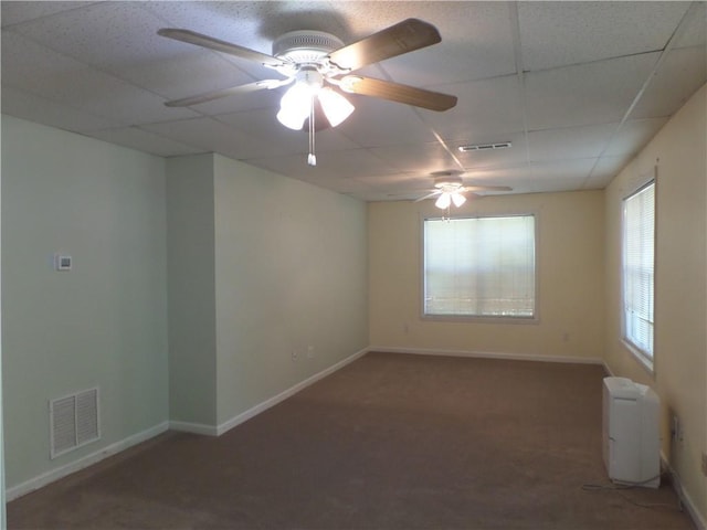 spare room featuring a paneled ceiling, ceiling fan, and dark colored carpet